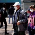 Personas adultas caminan usando tapabocas como medida preventiva para evitar el contagio del coronavirus en una calle de Bogotá