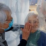 Marie-Paule y Marie-Josephe interactúan con su madre Colette, de 97 años, a través de una película de plástico dentro de una estructura de estilo burbuja que permite a las familias abrazarse sin riesgo de contaminación o contagio de COVID-19, instalada en el comedor del hogar de ancianos Residence du Carre d'Or en el Hospital Jeumont en Francia. 4 de diciembre, 2020. REUTERS/Pascal Rossignol