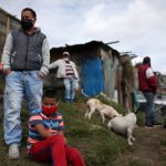Personas con máscaras faciales por la pandemia de COVID-19 permanecen frente a sus casas en Bogotá. REUTERS / Luisa González