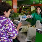 Una mujer recibe su cambio de una cajera en un supermercado en Bogotá. REUTERS/Luisa González