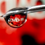 La palabra "COVID-19" se refleja en una gota en la aguja de una jeringa. REUTERS/Dado Ruvic/Illustration