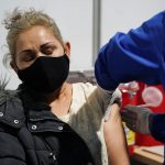 Una mujer recibe una vacuna contra el COVID-19 en el estacionamiento de un centro de exposiciones convertido en centro de vacunación, en Bogotá. REUTERS/Nathalia Angarita