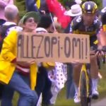 La mujer, con la pancarta, y a su izquierda el ciclista Tony Martin, que impacta contra ella