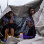 Dos mujeres se cubren de la lluvia bajo una lona en un campamento improvisado después de que la depresión tropical Grace pasó por el área tras el terremoto del sábado de magnitud 7,2, en Les Cayes, Haití. 17 de agosto, 2021. REUTERS/Ricardo Arduengo