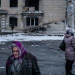 Unas mujeres pasan por delante de un edificio residencial destruido por los bombardeos en la región de Donetsk, en Ucrania .© UNICEF/Ashley Gilbertson
