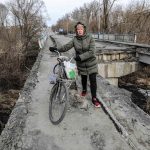 Una mujer pasa con su bicicleta en los restos del puente principal de la ciudad de Malyn destruido después de que la ciudad fuera bombardeada por aviones rusos, en Malyn, Ucrania, el 12 de marzo de 2022.. (Rusia, Ucrania) EFE/EPA/MIGUEL A. LOPES