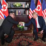 Donald Trump y Kim Jong Un se saludan. Foto: AFP